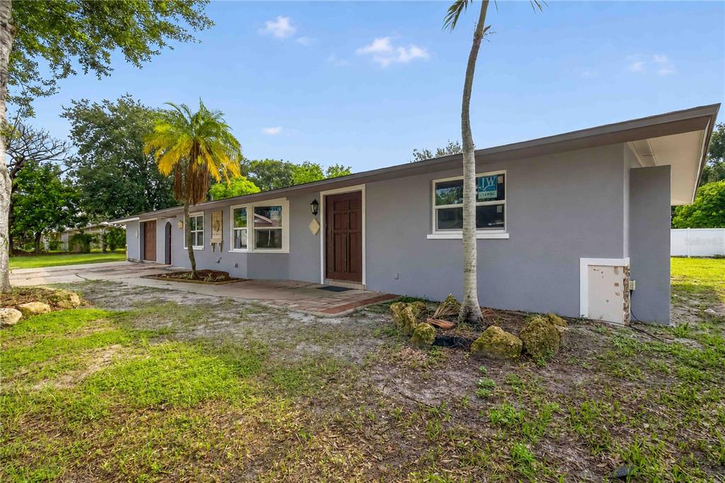 A gray, single-story ranch-style house features a brown front door, a palm tree, and a driveway — 4734 DELMONTE AVENUE, SARASOTA, FL