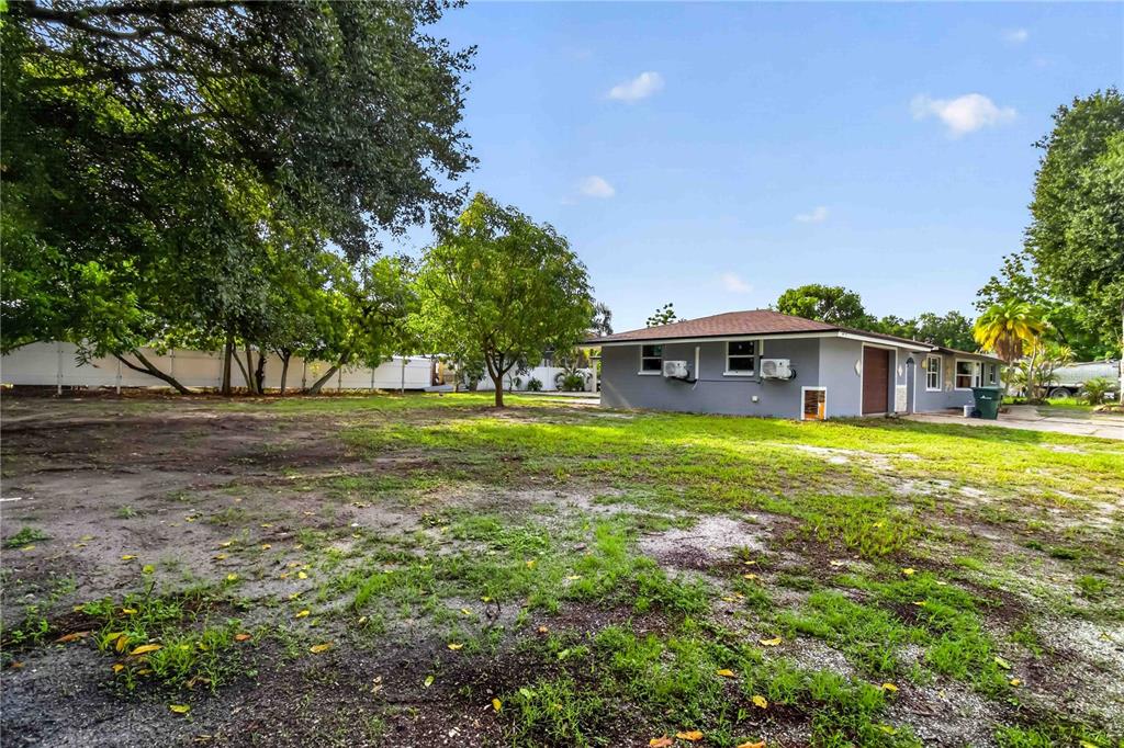 A gray house with a brown roof sits on a large, partially grassy lot — 4734 DELMONTE AVENUE, SARASOTA, FL