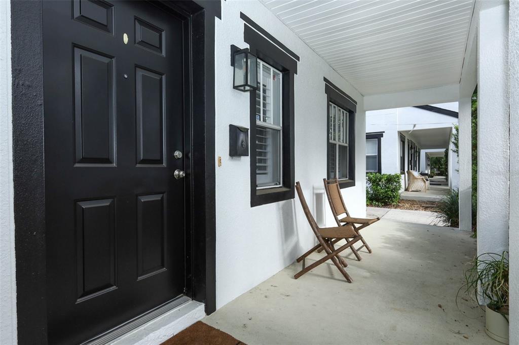 A two-story white house with black trim and a second-story balcony sits behind a hedge — 2202 ELIZABETH AVENUE UNIT B, ORLANDO, FL