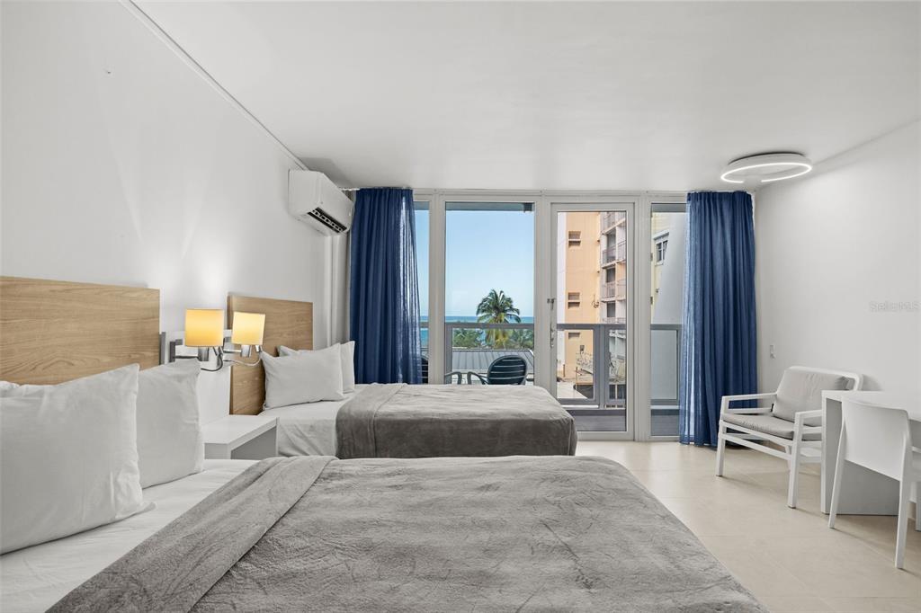 A hotel room features two beds, a balcony with ocean views, and white tile flooring — 6165 ISLA VERDE AVE. UNIT 377, CAROLINA, PR