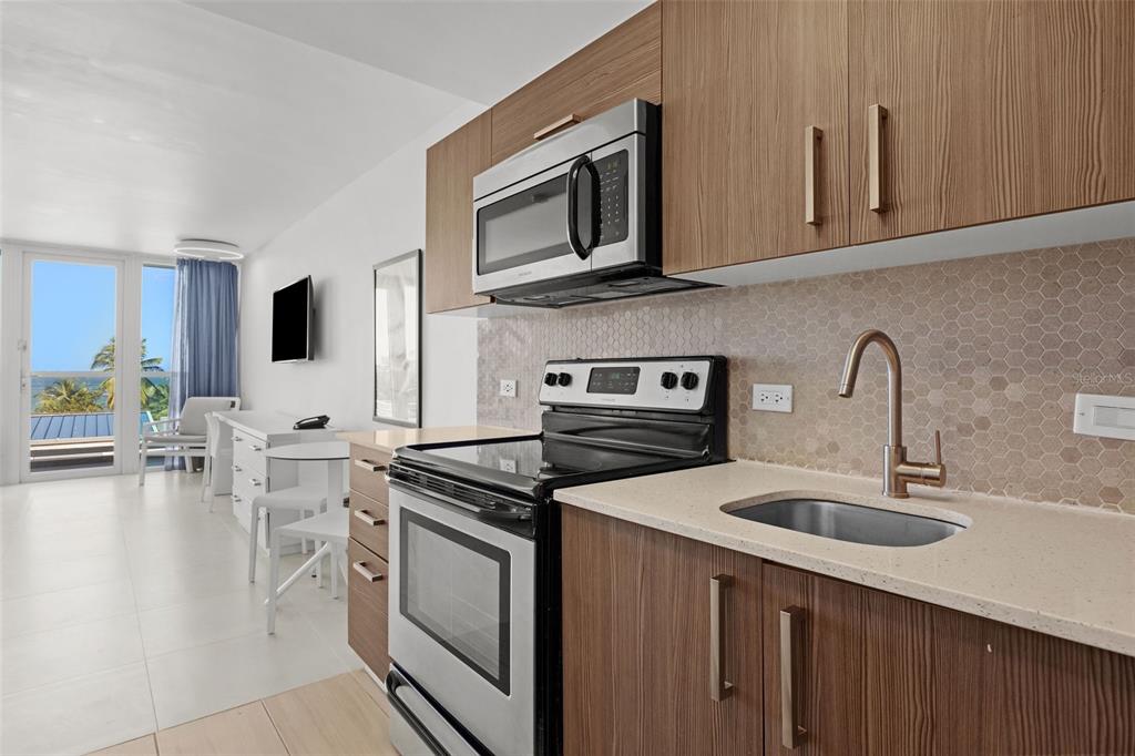 A modern kitchen with wood cabinets, stainless steel appliances, and a view of the ocean — 6165 ISLA VERDE AVE. UNIT 377, CAROLINA, PR