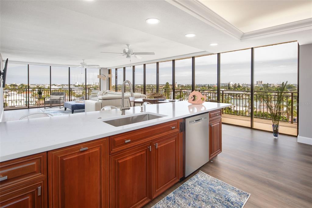A kitchen island with a stainless steel sink overlooks a living area with floor-to-ceiling windows — 7650 BAYSHORE DRIVE UNIT 606, TREASURE ISLAND, FL