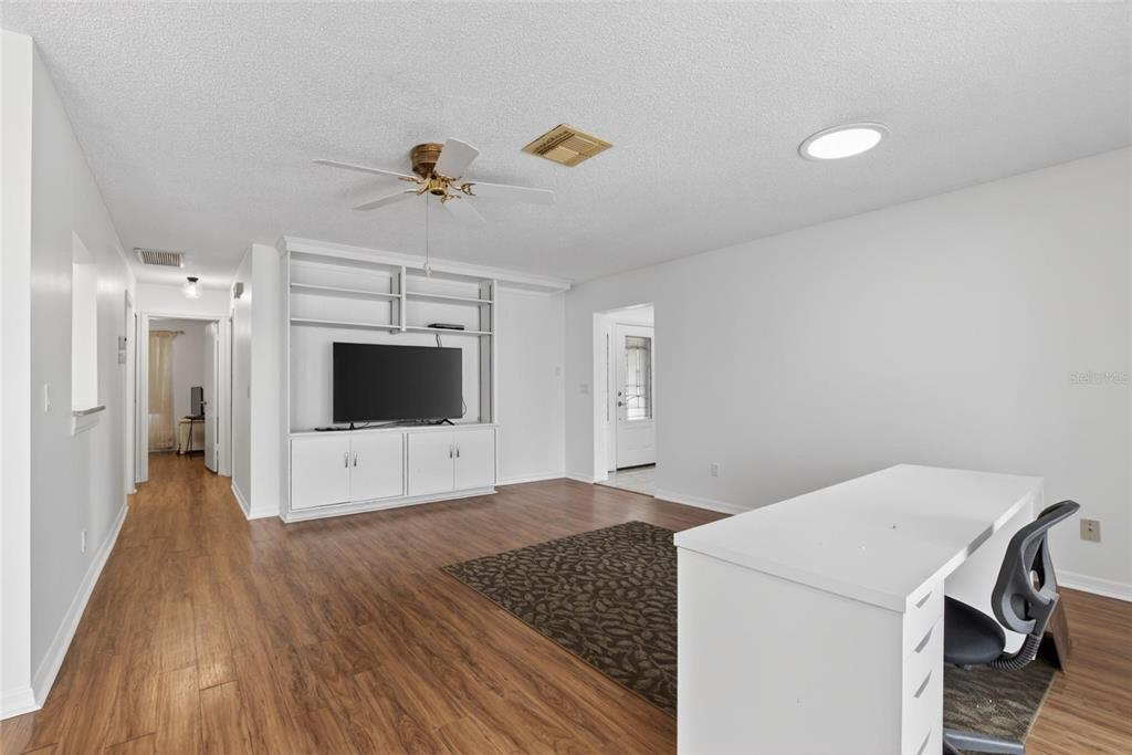 A living room features wood-look flooring, a white built-in media center, and a desk area — 213 GLENELLEN PLACE, SUN CITY CENTER, FL