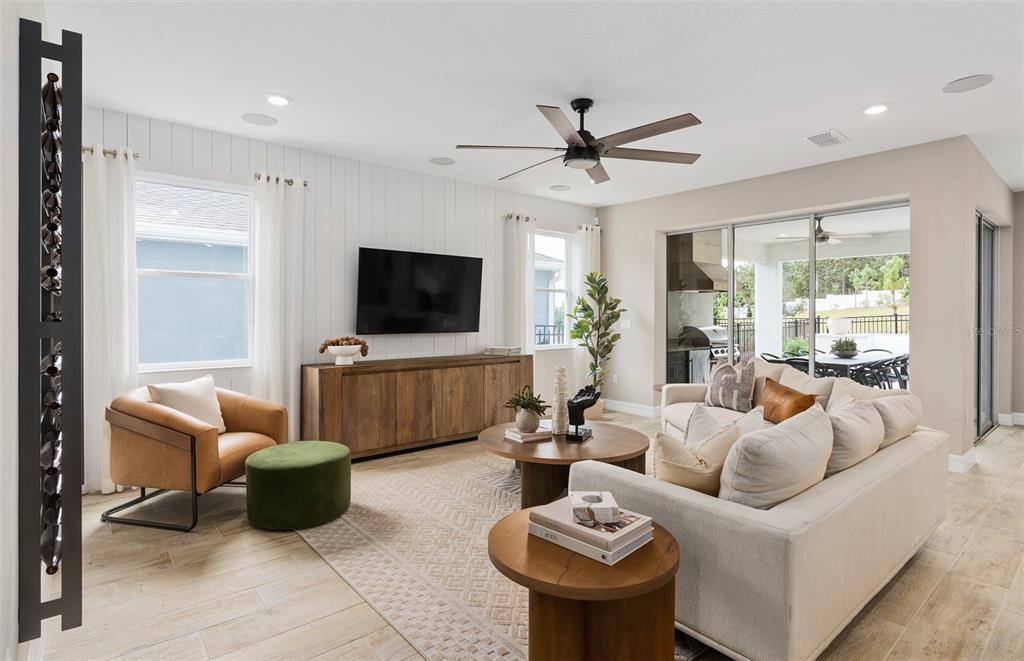 A living room features a white shiplap wall, a large television, and a neutral sofa — 2810 LOFTBRIDGE ROAD, MINNEOLA, FL