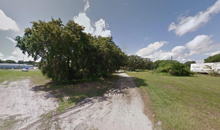 A dirt path leads through a grassy lot with mature trees and a distant trailer — 60 E STREET, LAKE WALES, FL