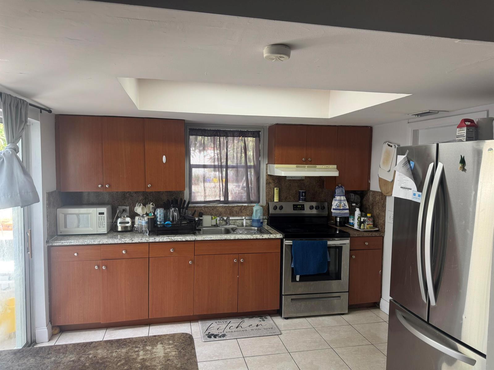 A kitchen features wood cabinets, granite countertops, stainless steel appliances, and a recessed ceiling light — 910 N F Street, FL 33460, FL