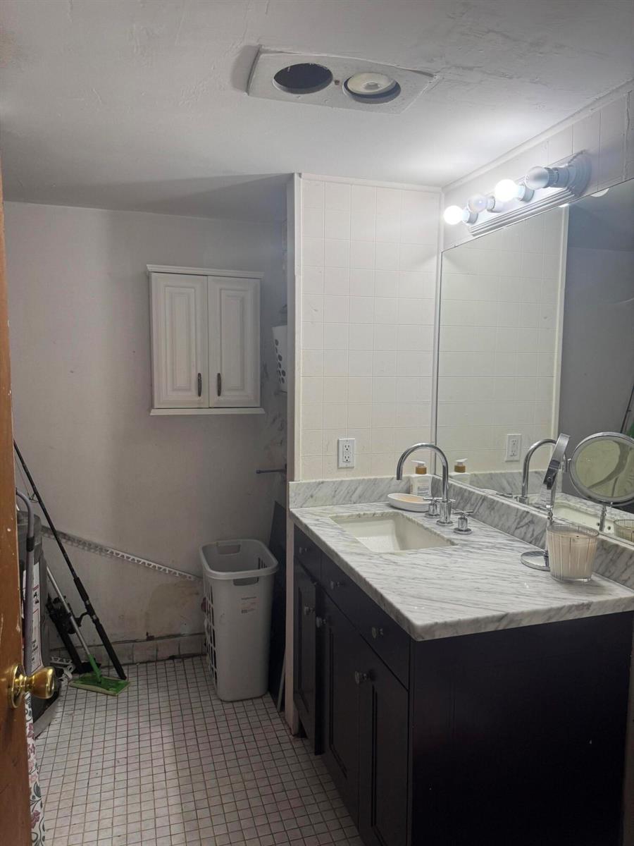 A bathroom features a dark vanity with a marble countertop, a wall-mounted cabinet, and tile flooring — 910 N F Street, FL 33460, FL