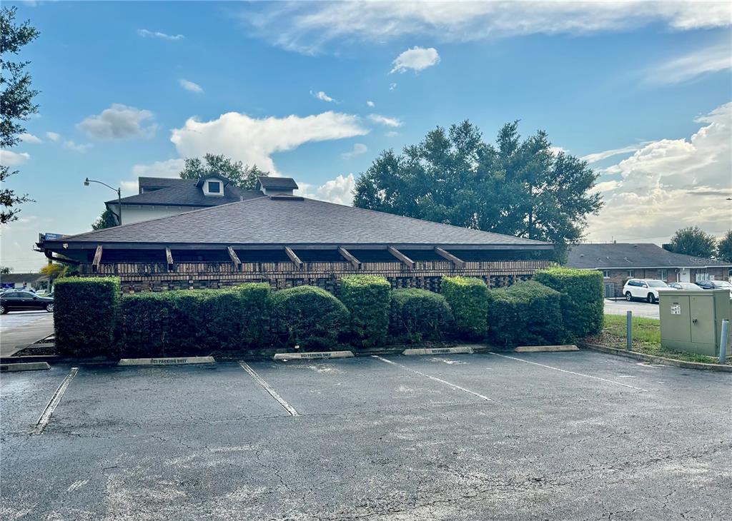 A low-slung building with a brick facade and overhanging roof sits behind a parking lot — 1619 E VINE STREET, KISSIMMEE, FL