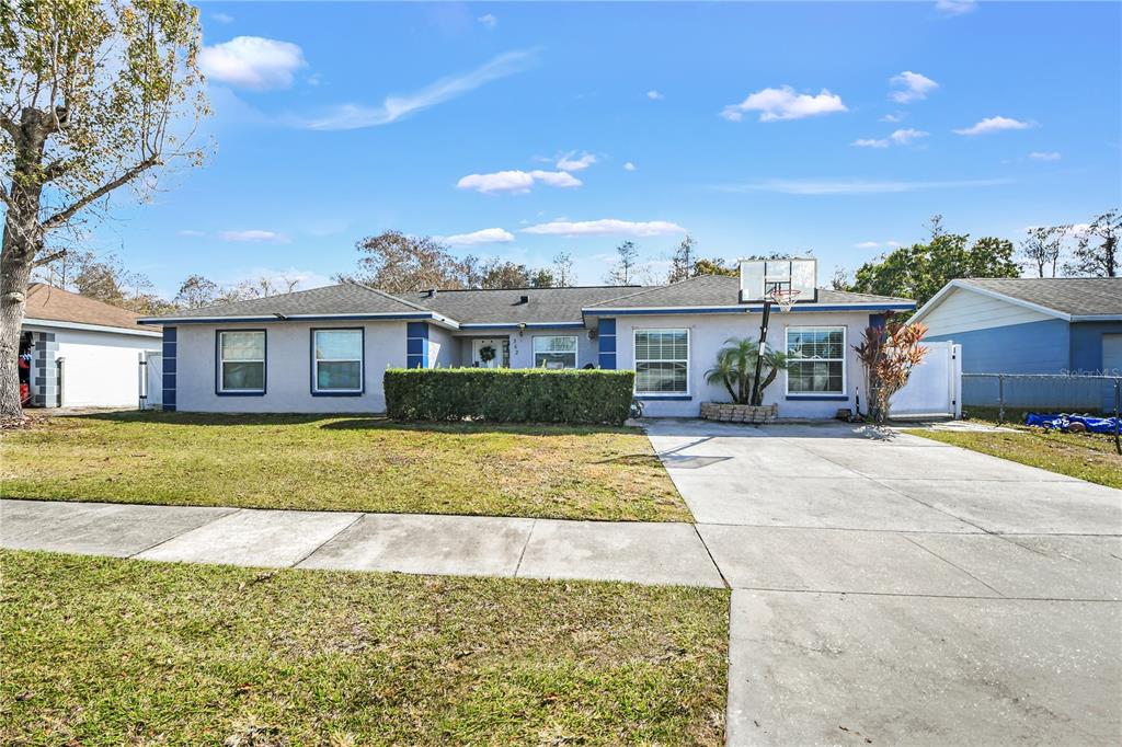 A single-story house with a concrete driveway, basketball hoop, and a manicured front hedge — 362 IOWA WOODS CIRCLE W, ORLANDO, FL