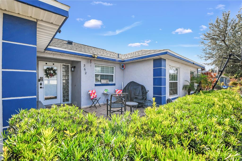 A single-story house exterior features a blue-trimmed entrance, a front patio, and green landscaping — 362 IOWA WOODS CIRCLE W, ORLANDO, FL
