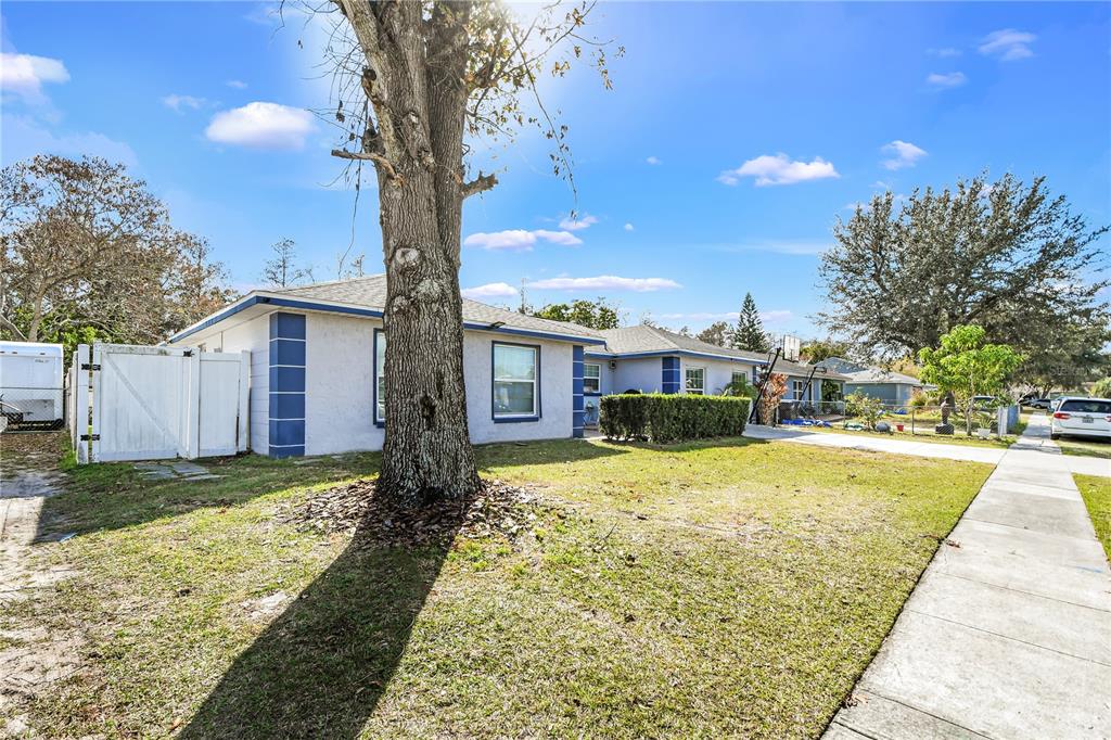 A single-story house with light-colored siding, blue trim, and a large tree in the yard — 362 IOWA WOODS CIRCLE W, ORLANDO, FL