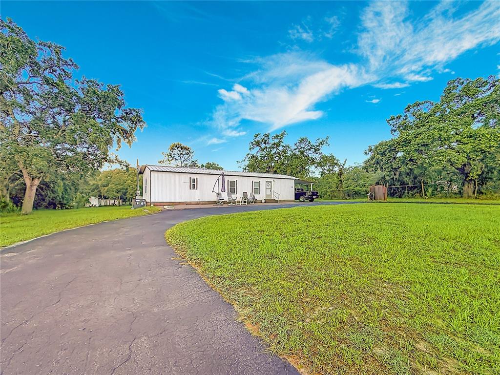 A white mobile home sits on a grassy lot with a paved driveway and trees — 5396 W RICHLAND LANE, HOMOSASSA, FL