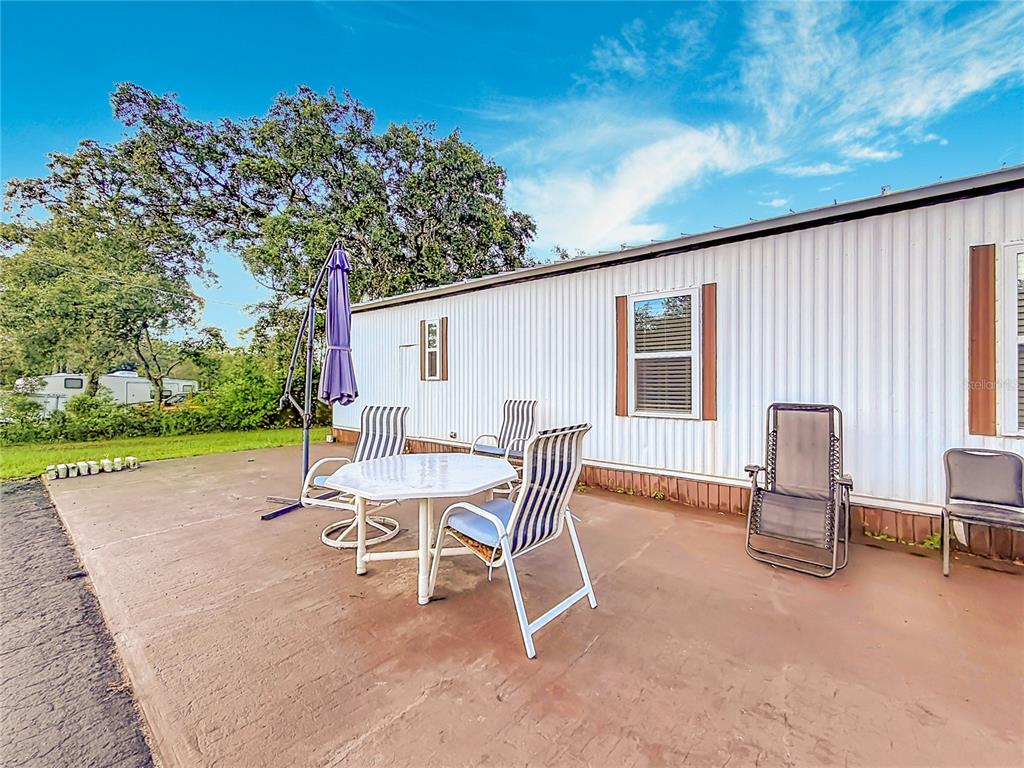 A patio with a table and chairs sits outside a white mobile home — 5396 W RICHLAND LANE, HOMOSASSA, FL
