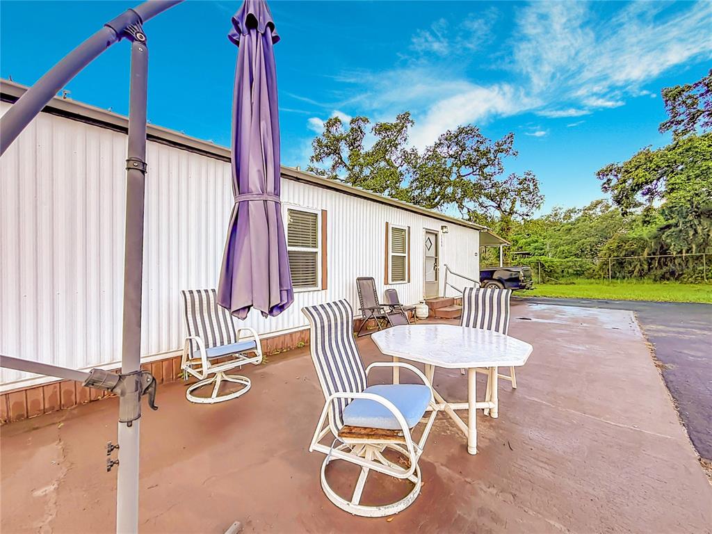 A patio with a table, chairs, and a closed umbrella sits beside a mobile home — 5396 W RICHLAND LANE, HOMOSASSA, FL