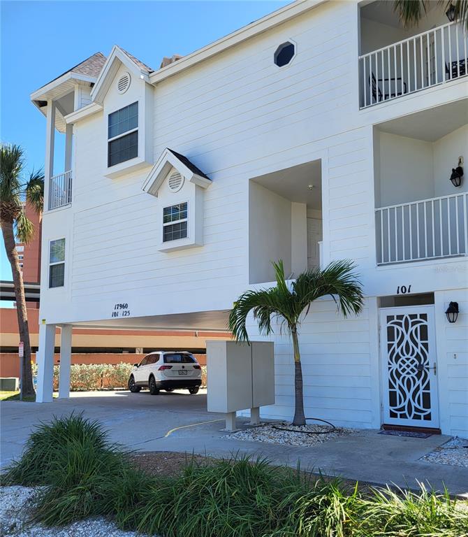 The exterior of a white multi-story building features a covered parking area and unit 101 — 17960 GULF BOULEVARD UNIT 101, REDINGTON SHORES, FL