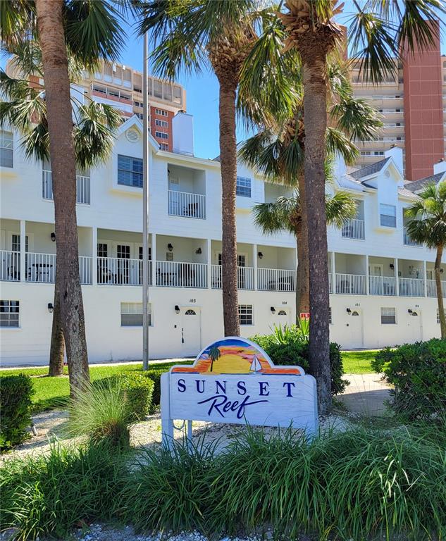 A white multi-story apartment building features balconies and a Sunset Reef sign in the foreground — 17960 GULF BOULEVARD UNIT 101, REDINGTON SHORES, FL