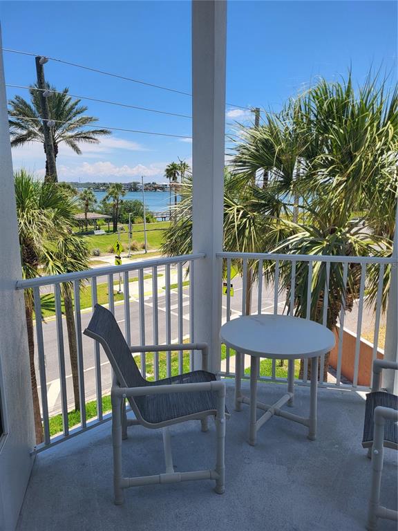 A balcony features a small round table and a chair overlooking a street and water — 17960 GULF BOULEVARD UNIT 101, REDINGTON SHORES, FL