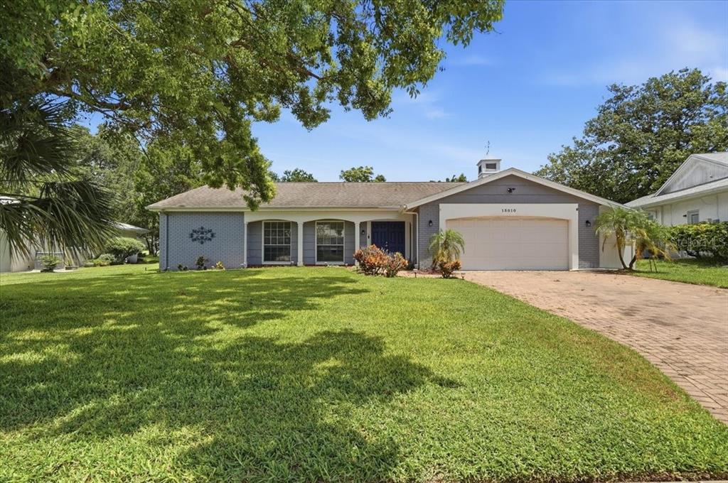 A single-story house with a gray brick exterior, a two-car garage, and a large front lawn — 13010 PEBBLE BEACH CIRCLE, HUDSON, FL