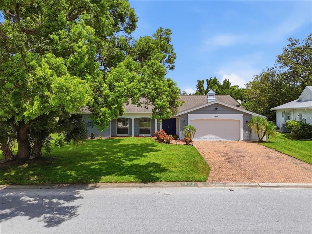 A single-story house with a brick driveway, a two-car garage, and a large front yard — 13010 PEBBLE BEACH CIRCLE, HUDSON, FL