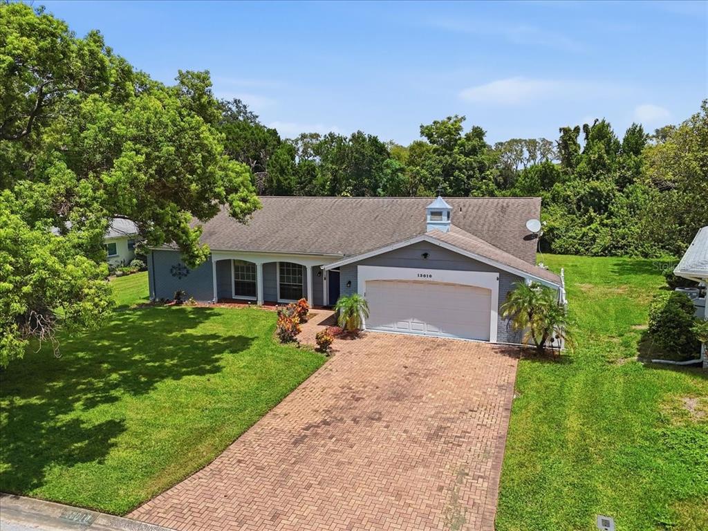 An aerial view of a single-story house with a brick driveway and a two-car garage — 13010 PEBBLE BEACH CIRCLE, HUDSON, FL