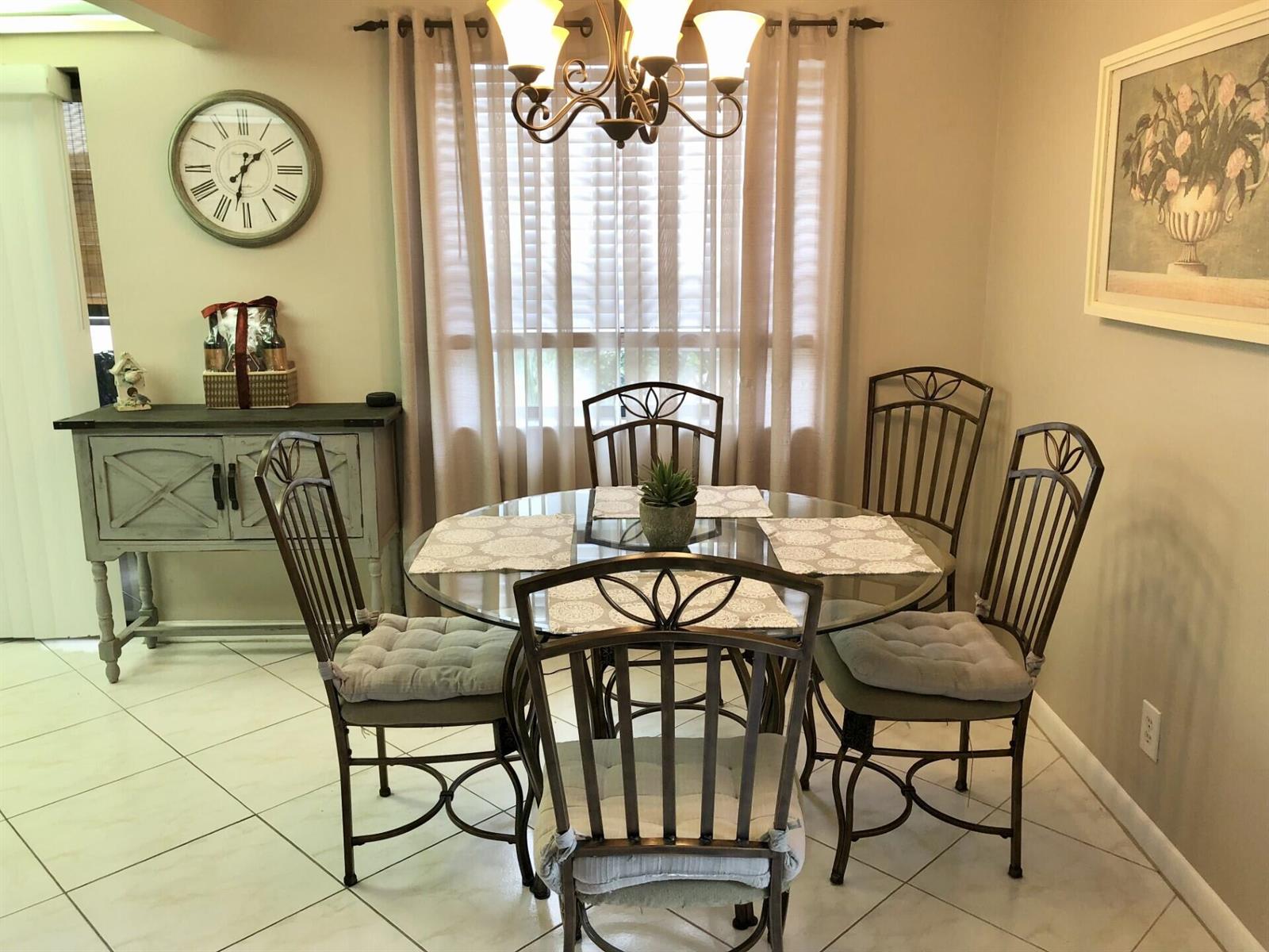A dining room features a glass-topped table with four metal chairs and a side cabinet — 499 Piedmont K, Delray Beach FL 33484, DELRAY BEACH, FL