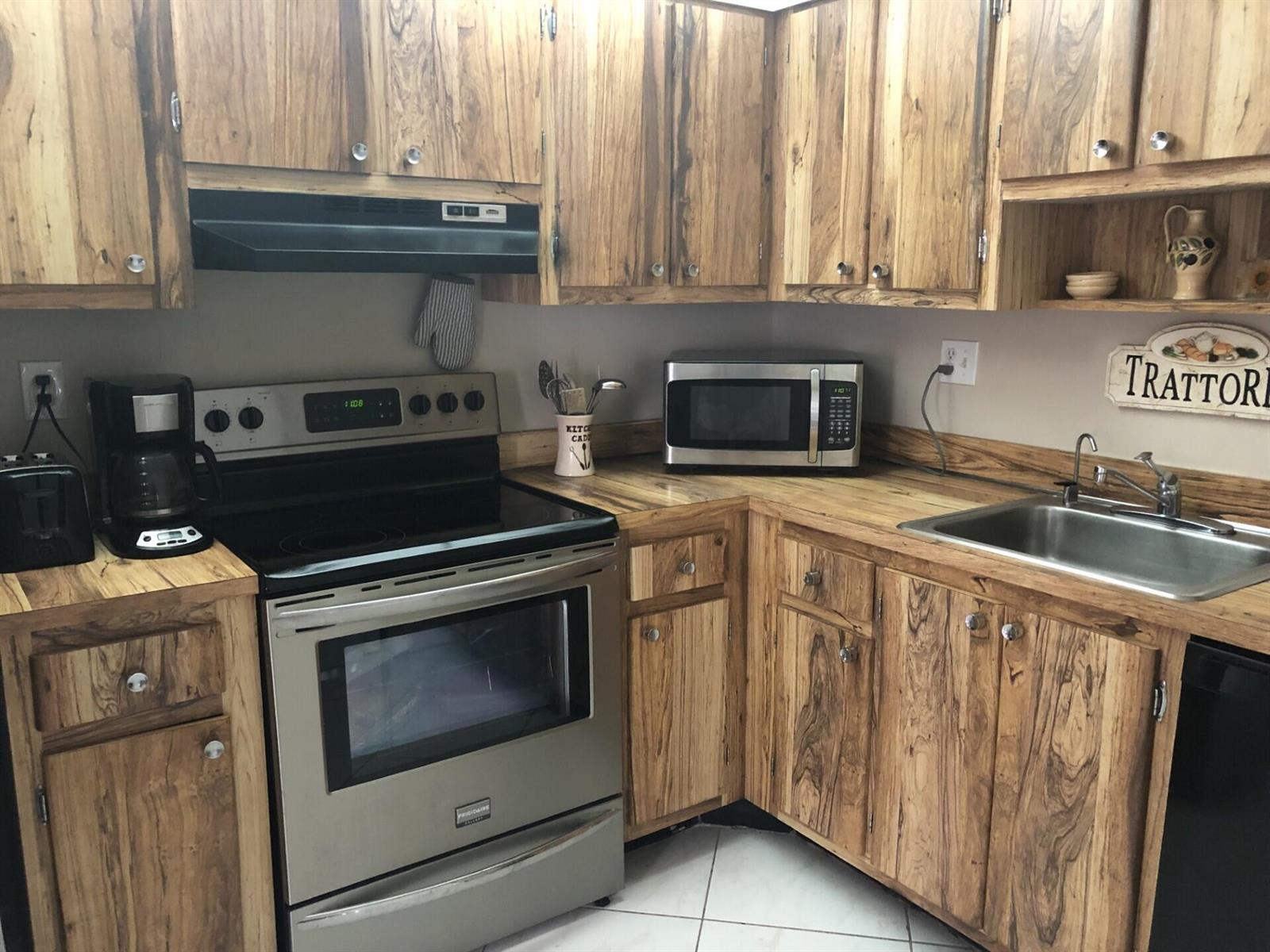 A kitchen with wood-grain cabinets, stainless steel appliances, and a stainless steel sink — 499 Piedmont K, Delray Beach FL 33484, DELRAY BEACH, FL