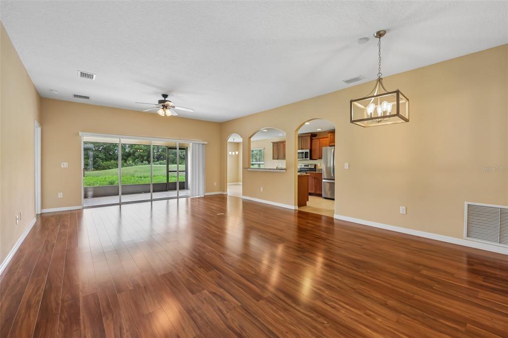 A grassy backyard features a concrete patio, a small tree, and a paved walking path — 4025 ARLINGTON RIDGE BOULEVARD, LEESBURG, FL