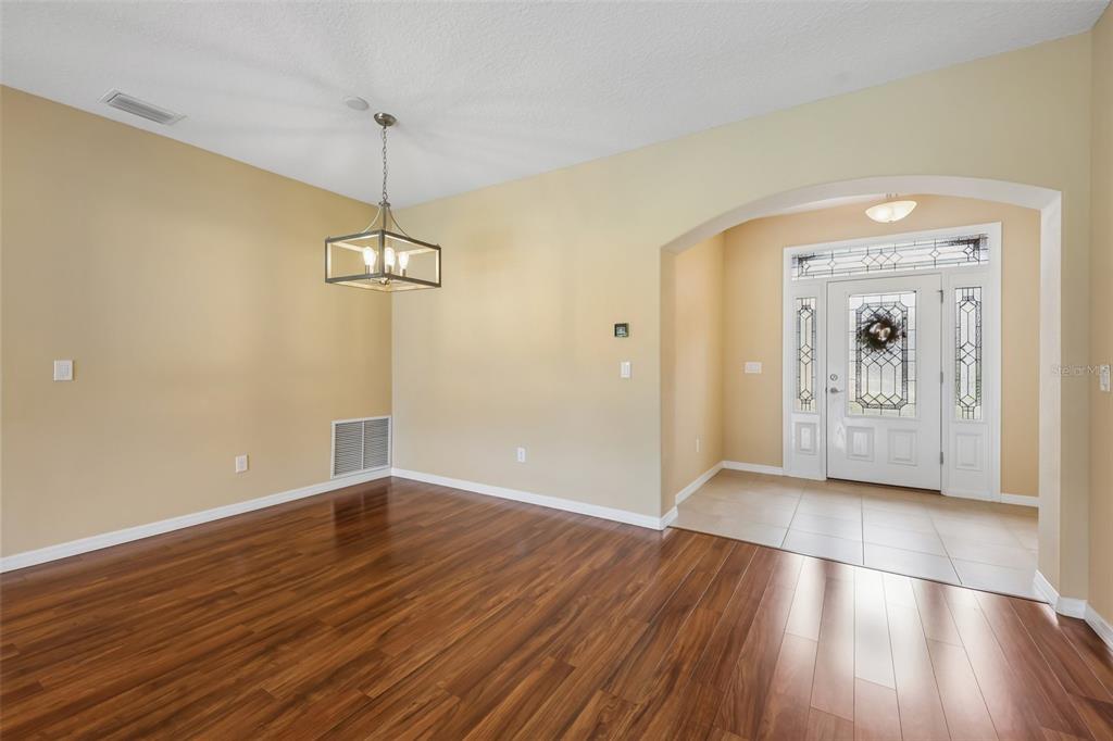 An open-concept living and dining area features hardwood floors, a kitchen pass-through, and sliding doors — 4025 ARLINGTON RIDGE BOULEVARD, LEESBURG, FL