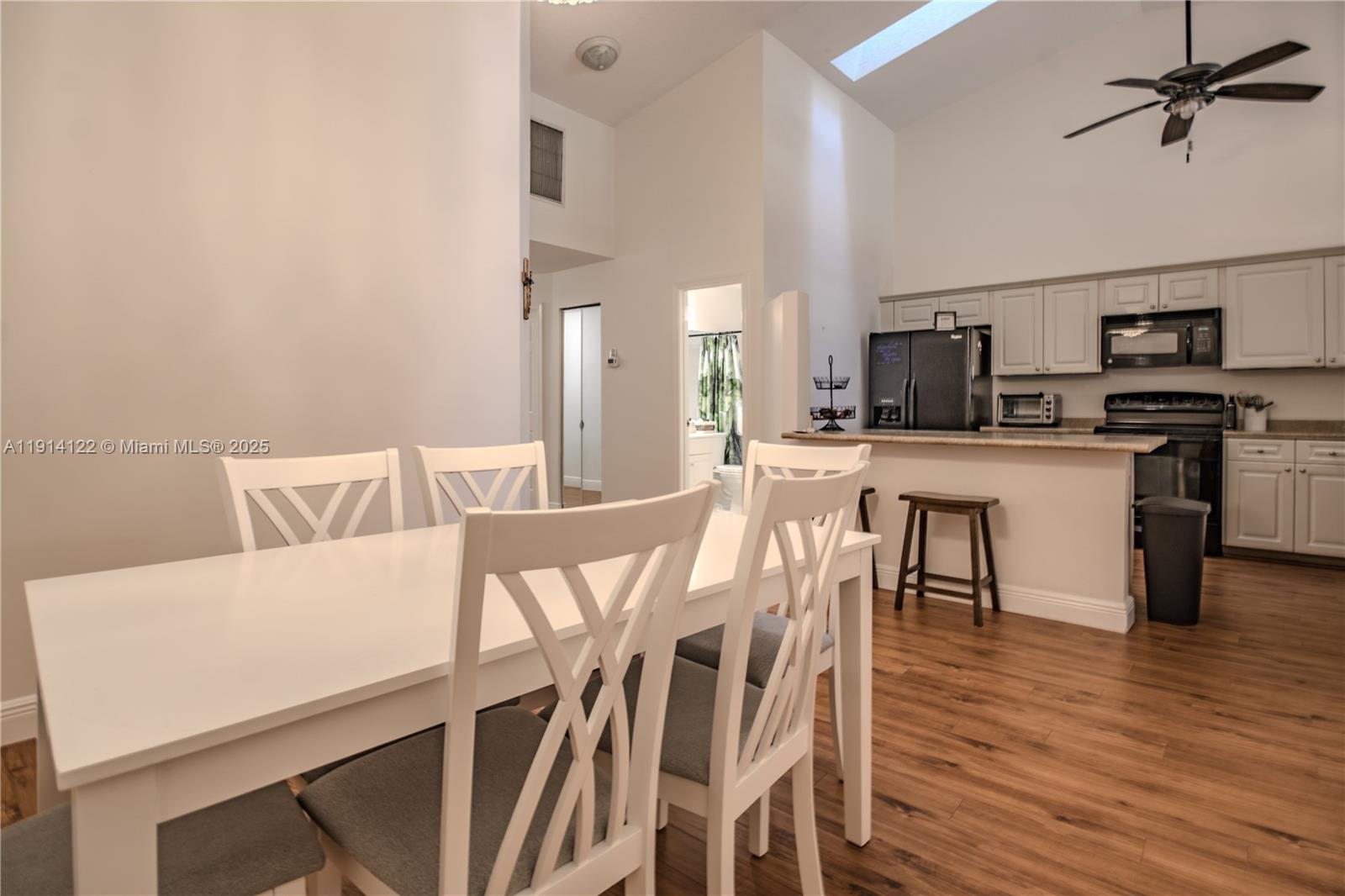 A dining area with a white table and chairs sits adjacent to an open kitchen — 7652 S Pinewalk Dr S # 139, Margate FL 33063, MARGATE, FL