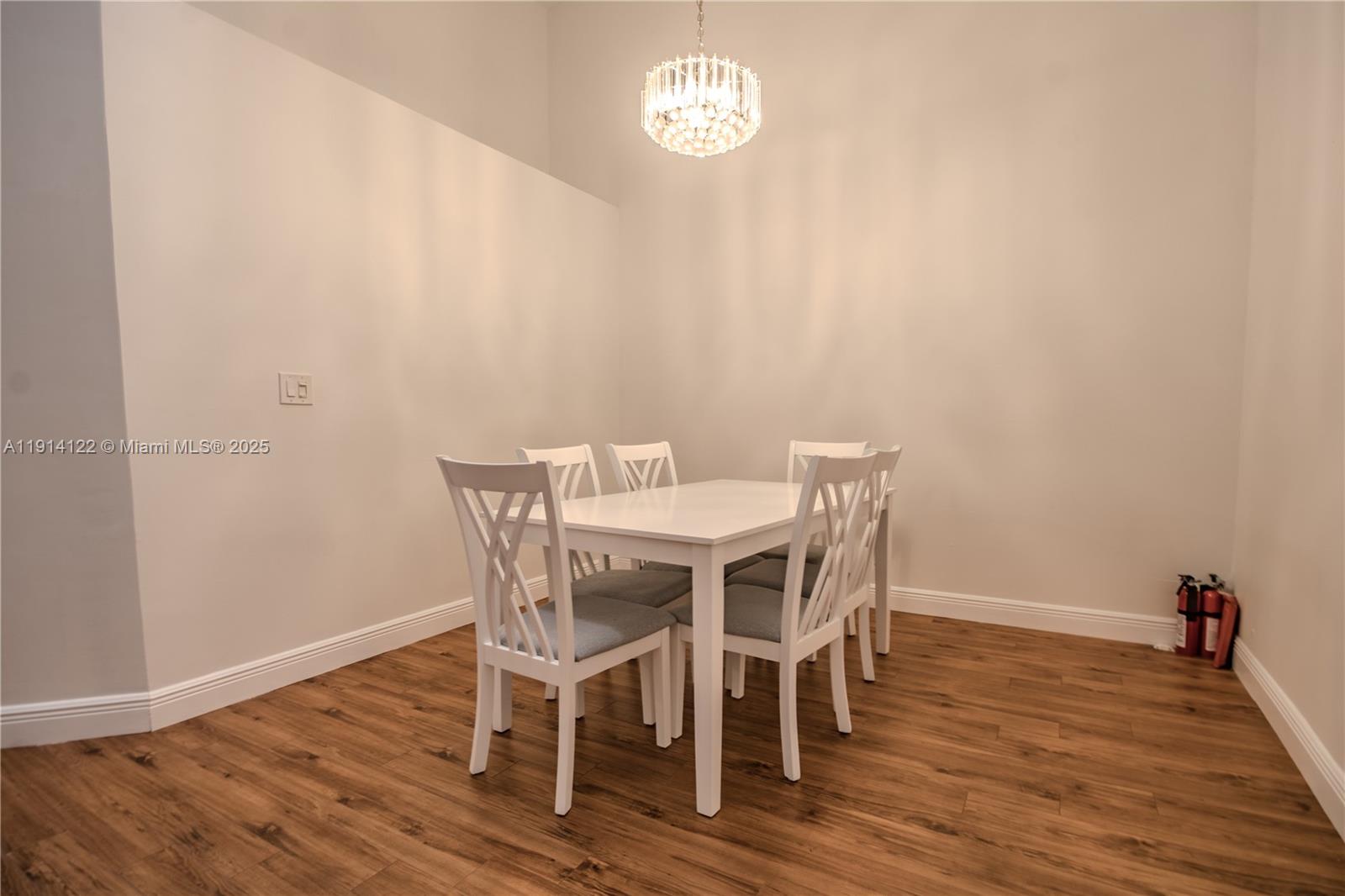 A dining area features a white table, four chairs, and a crystal chandelier — 7652 S Pinewalk Dr S # 139, Margate FL 33063, MARGATE, FL
