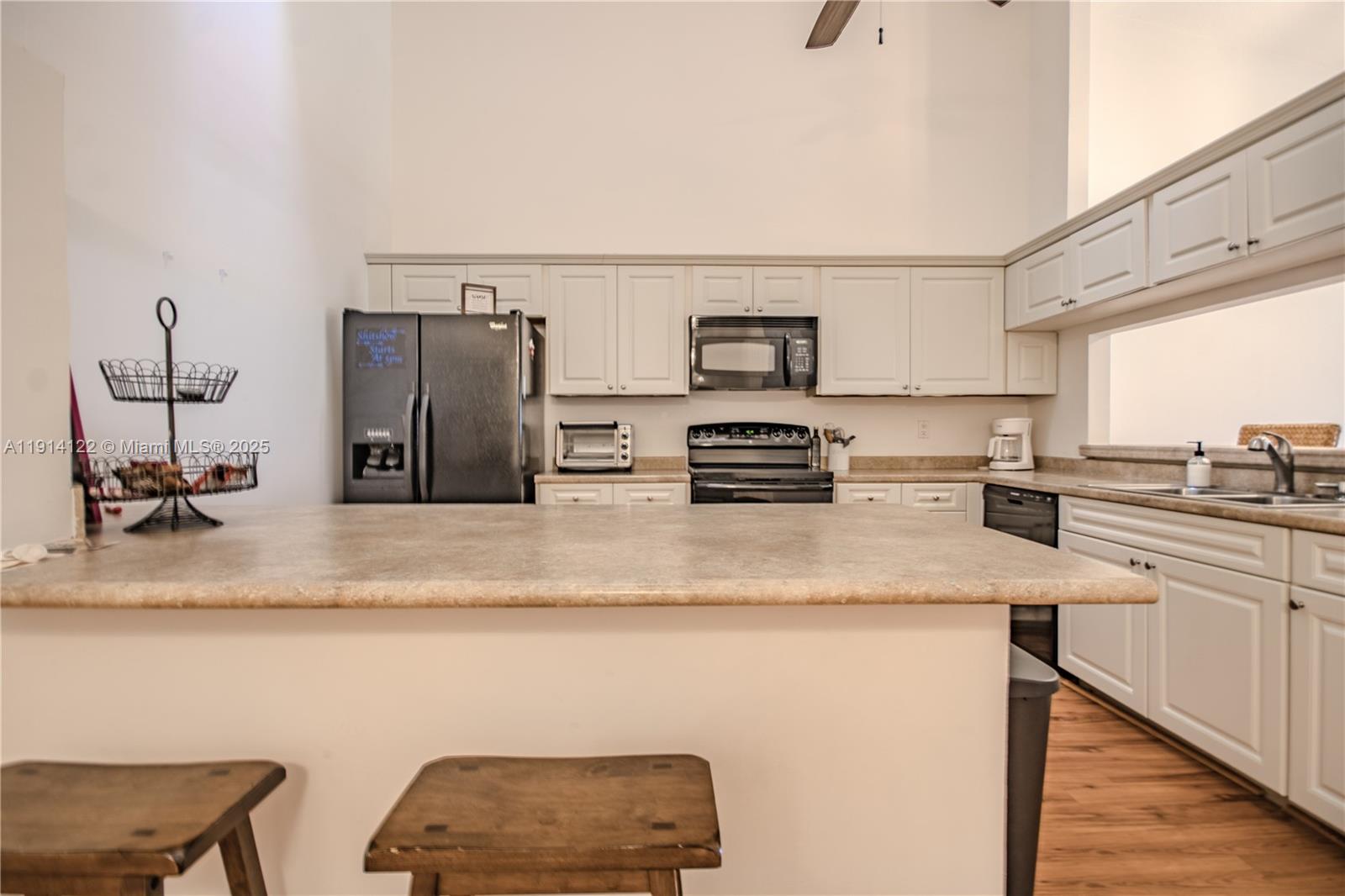 A kitchen features white cabinets, a large island with a countertop, and black appliances — 7652 S Pinewalk Dr S # 139, Margate FL 33063, MARGATE, FL