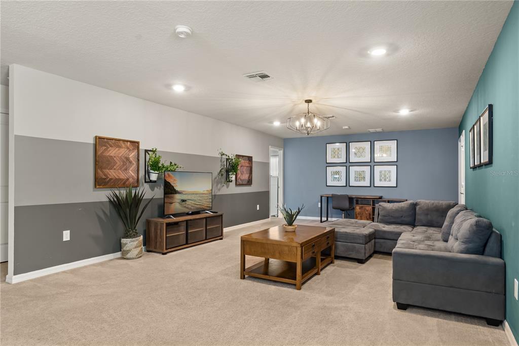 A living room features a gray sectional sofa, a television on a console, and blue walls — 2036 LELANI CIR, DAVENPORT, FL