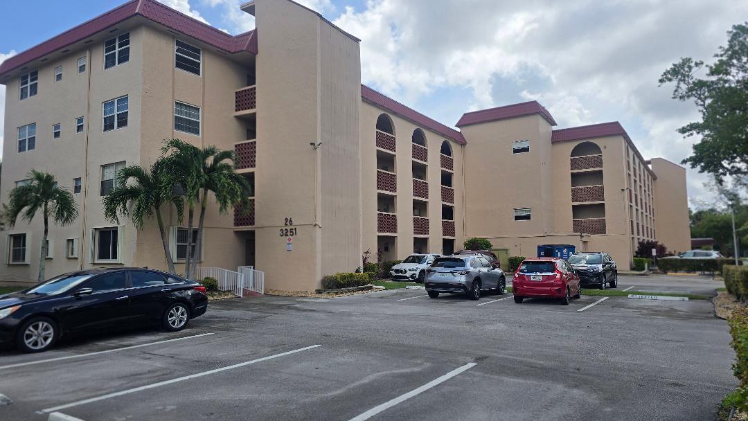A multi-story apartment building with a tan exterior and a parking lot in front — 3251 Holiday Springs Boulevard # 302, Margate FL 33063, MARGATE, FL