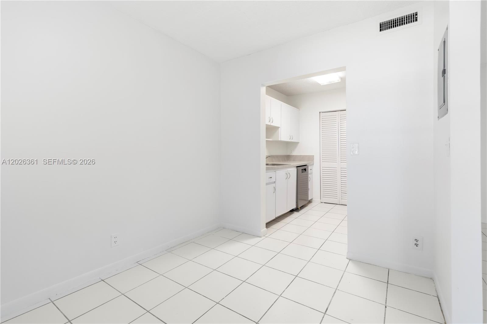 A white-walled dining area with tiled floors leads into a small, galley-style kitchen — 500 NE 2nd St # 223, Dania Beach FL 33004, DANIA BEACH, FL