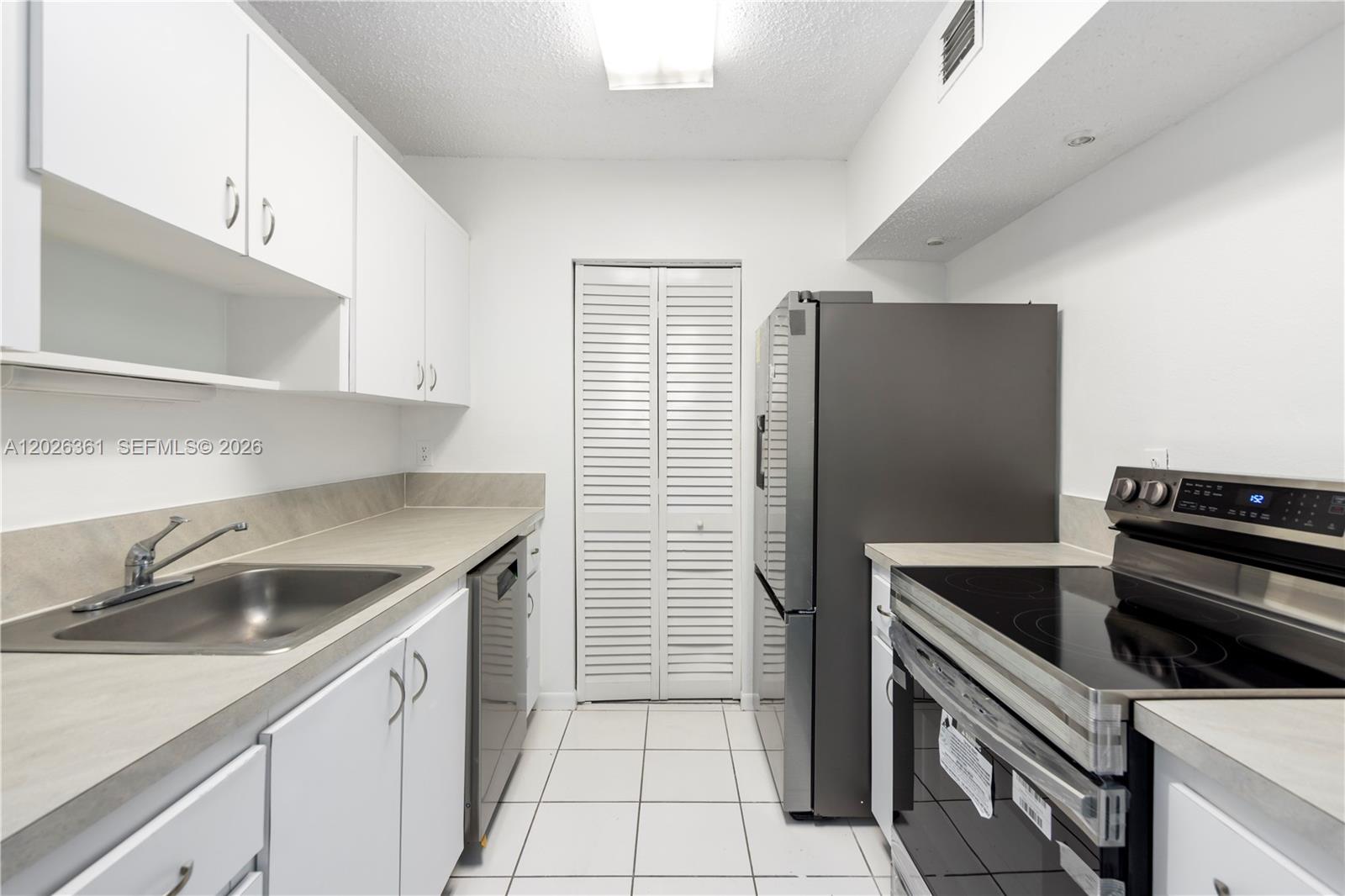 A galley kitchen features white cabinets, stainless steel appliances, and light-colored countertops — 500 NE 2nd St # 223, Dania Beach FL 33004, DANIA BEACH, FL