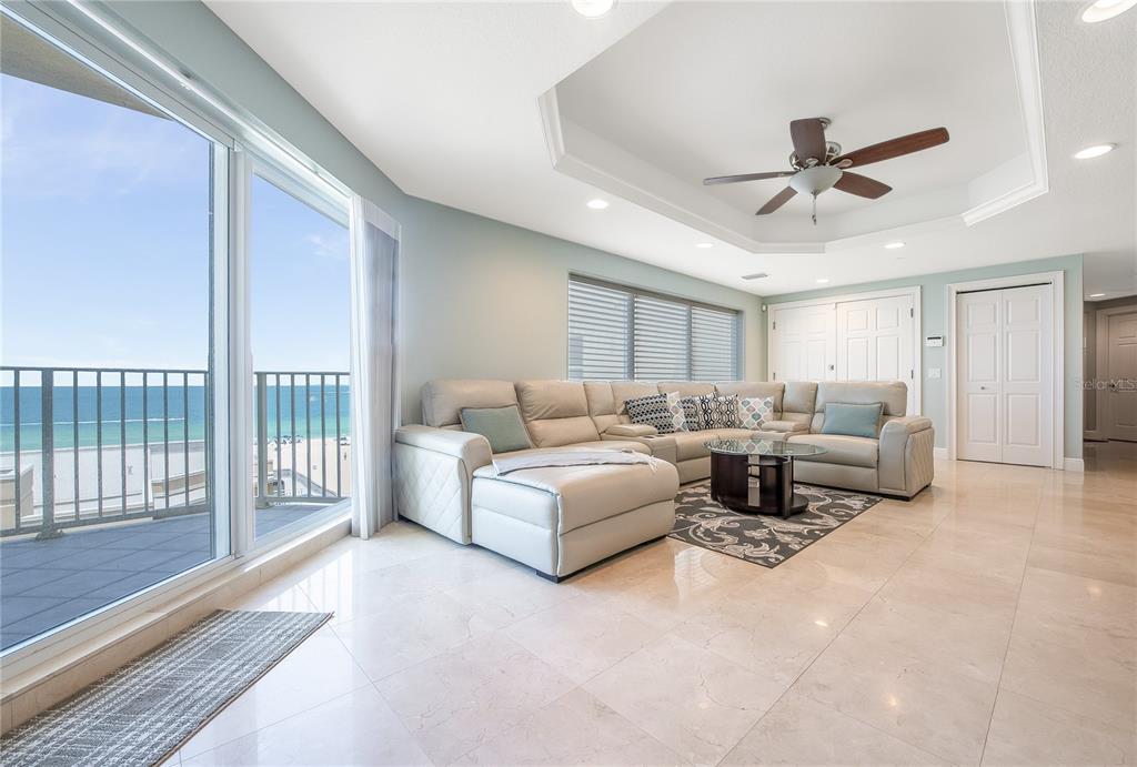 A living room with a large sectional sofa, tile floors, and a balcony overlooking the ocean — 15 SOMERSET STREET UNIT 603, CLEARWATER BEACH, FL