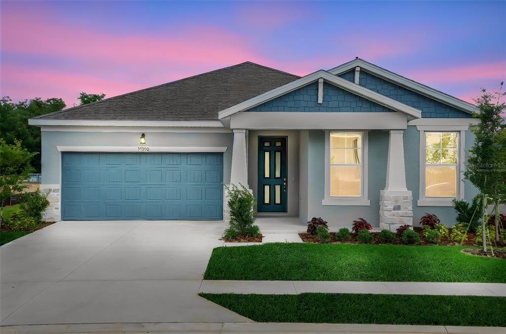 A single-story house with a blue garage door, gray siding, and a covered front porch — 35200 TUSCAN HILL ROAD, DADE CITY, FL