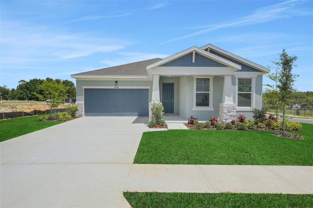 A single-story house with a blue garage door, gray siding, and a covered front porch — 35200 TUSCAN HILL ROAD, DADE CITY, FL