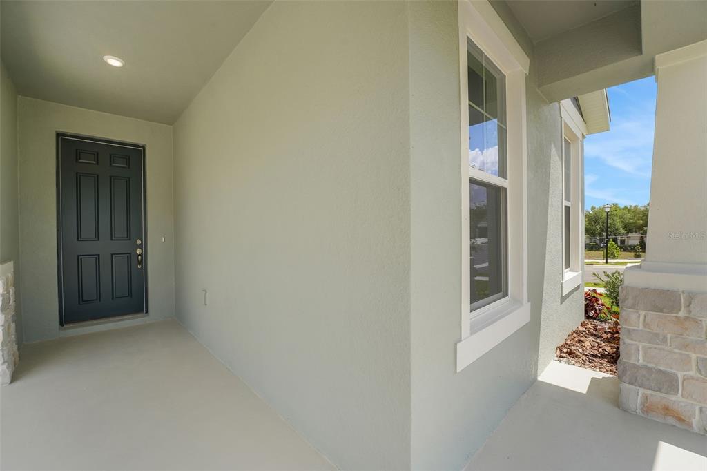 A covered front porch features a dark gray door, a window, and stone column accents — 35200 TUSCAN HILL ROAD, DADE CITY, FL