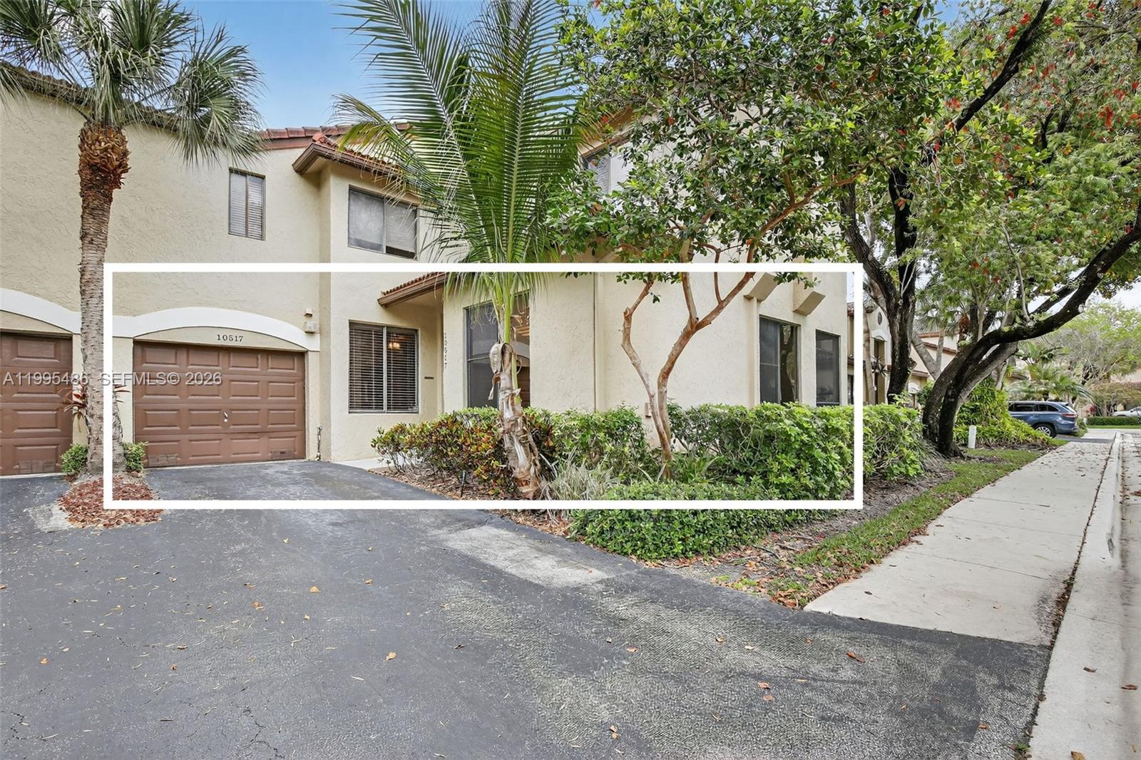 The exterior of a two-story townhouse features a brown garage door and landscaping — 10517 NW 10th St # 131, Plantation FL 33322, PLANTATION, FL