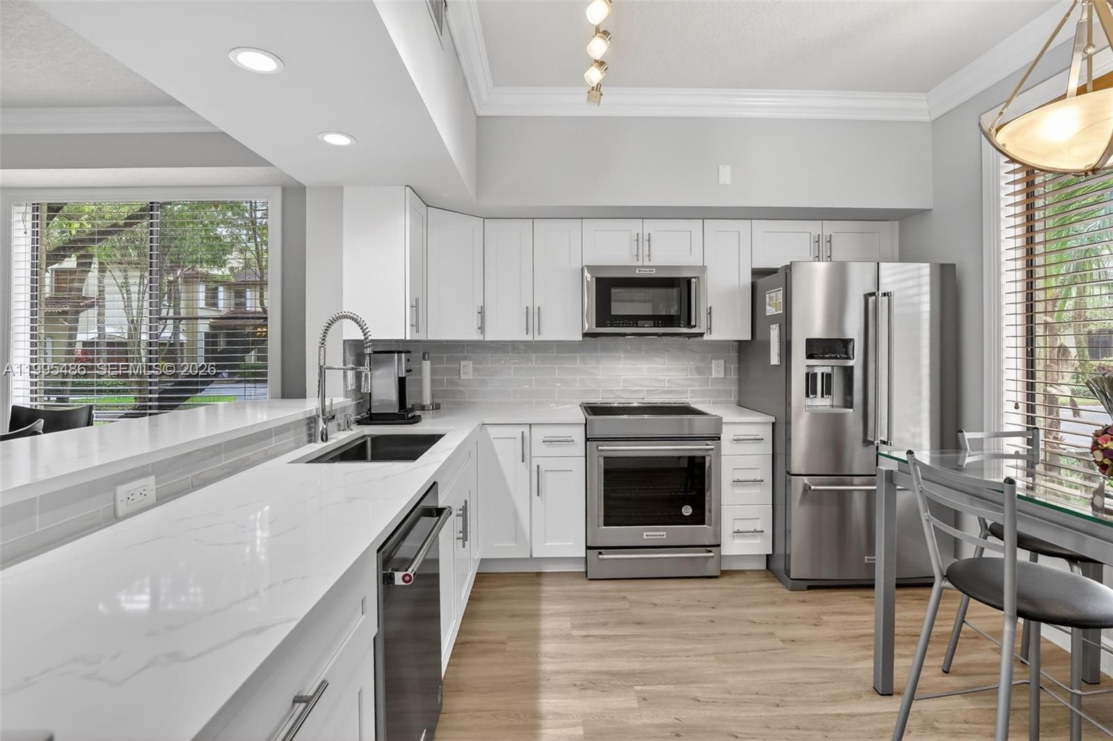 A modern kitchen features white cabinets, stainless steel appliances, and a white marble-look countertop — 10517 NW 10th St # 131, Plantation FL 33322, PLANTATION, FL