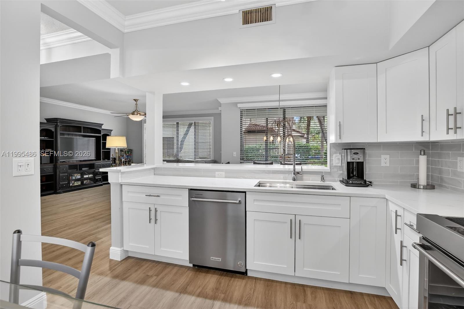 A modern kitchen features white cabinets, stainless steel appliances, and a pass-through window — 10517 NW 10th St # 131, Plantation FL 33322, PLANTATION, FL