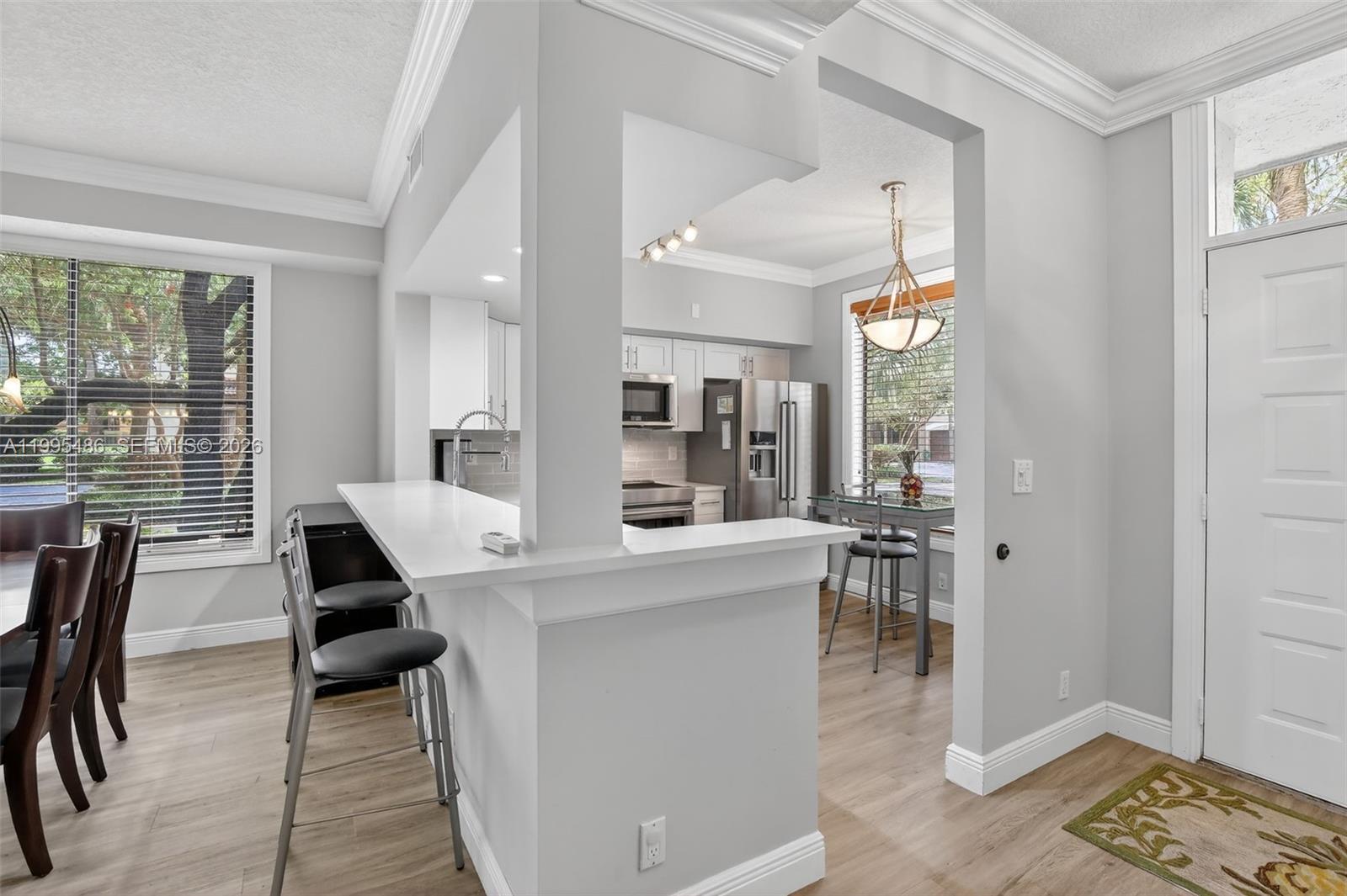 A kitchen features a white breakfast bar, stainless steel appliances, and light wood-look flooring — 10517 NW 10th St # 131, Plantation FL 33322, PLANTATION, FL