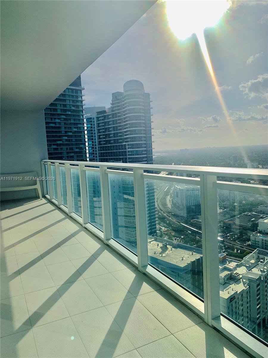 A high-rise balcony with glass railings overlooks a city skyline and a highway — 1080 Brickell Ave # 4009, Miami FL 33131, MIAMI, FL