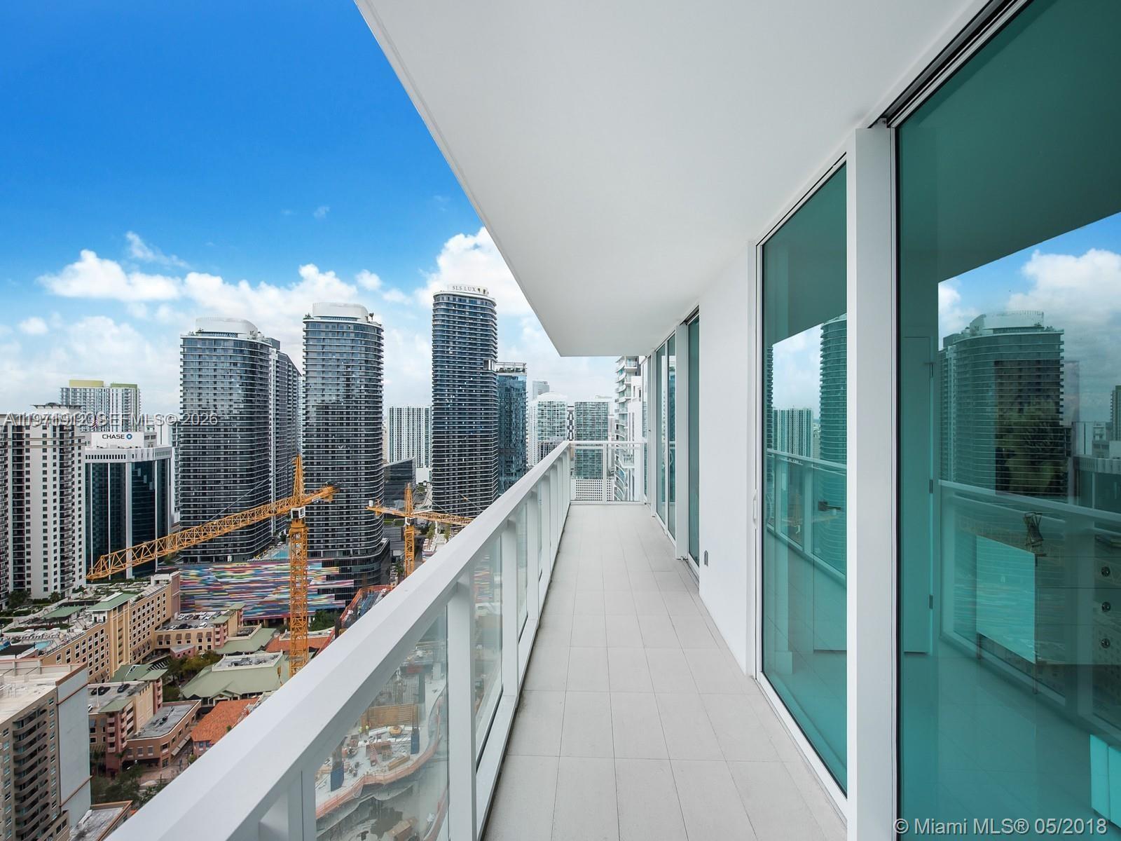 A high-rise balcony with a glass railing overlooks a city skyline with construction cranes — 1080 Brickell Ave # 4009, Miami FL 33131, MIAMI, FL