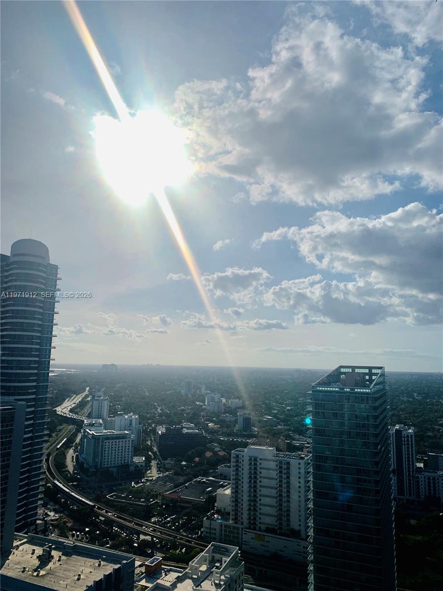A high-angle view shows a cityscape with tall buildings and a railway under sunlight — 1080 Brickell Ave # 4009, Miami FL 33131, MIAMI, FL