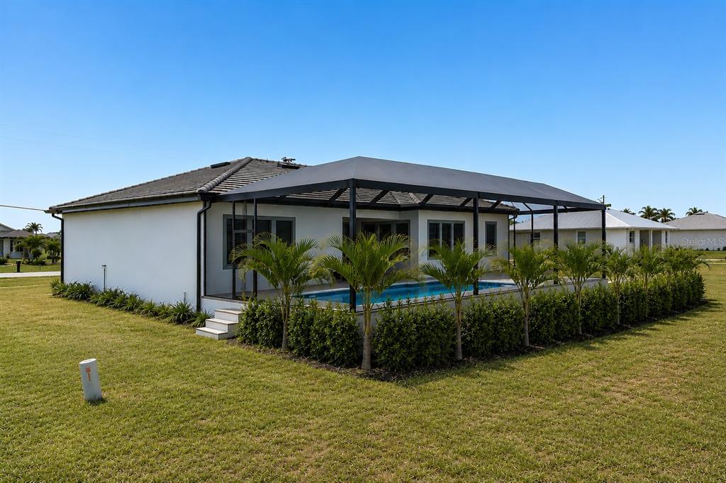 A white house features a screened-in pool patio with palm trees and a grassy yard — 17315 CAPE HORN BOULEVARD, PUNTA GORDA, FL