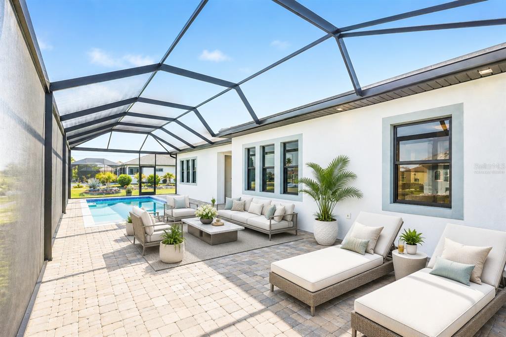 A covered patio features a swimming pool, outdoor seating, and lounge chairs on a paved deck — 17315 CAPE HORN BOULEVARD, PUNTA GORDA, FL