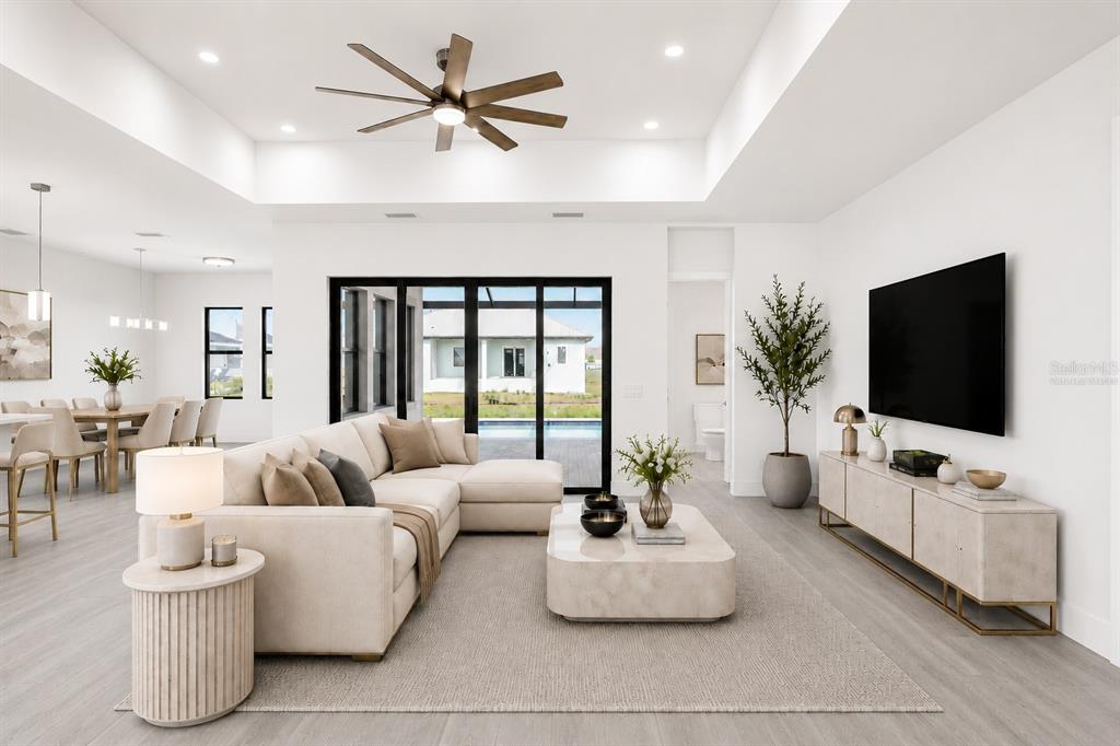 A modern living room features a sectional sofa, coffee table, television, and large sliding glass doors — 17315 CAPE HORN BOULEVARD, PUNTA GORDA, FL