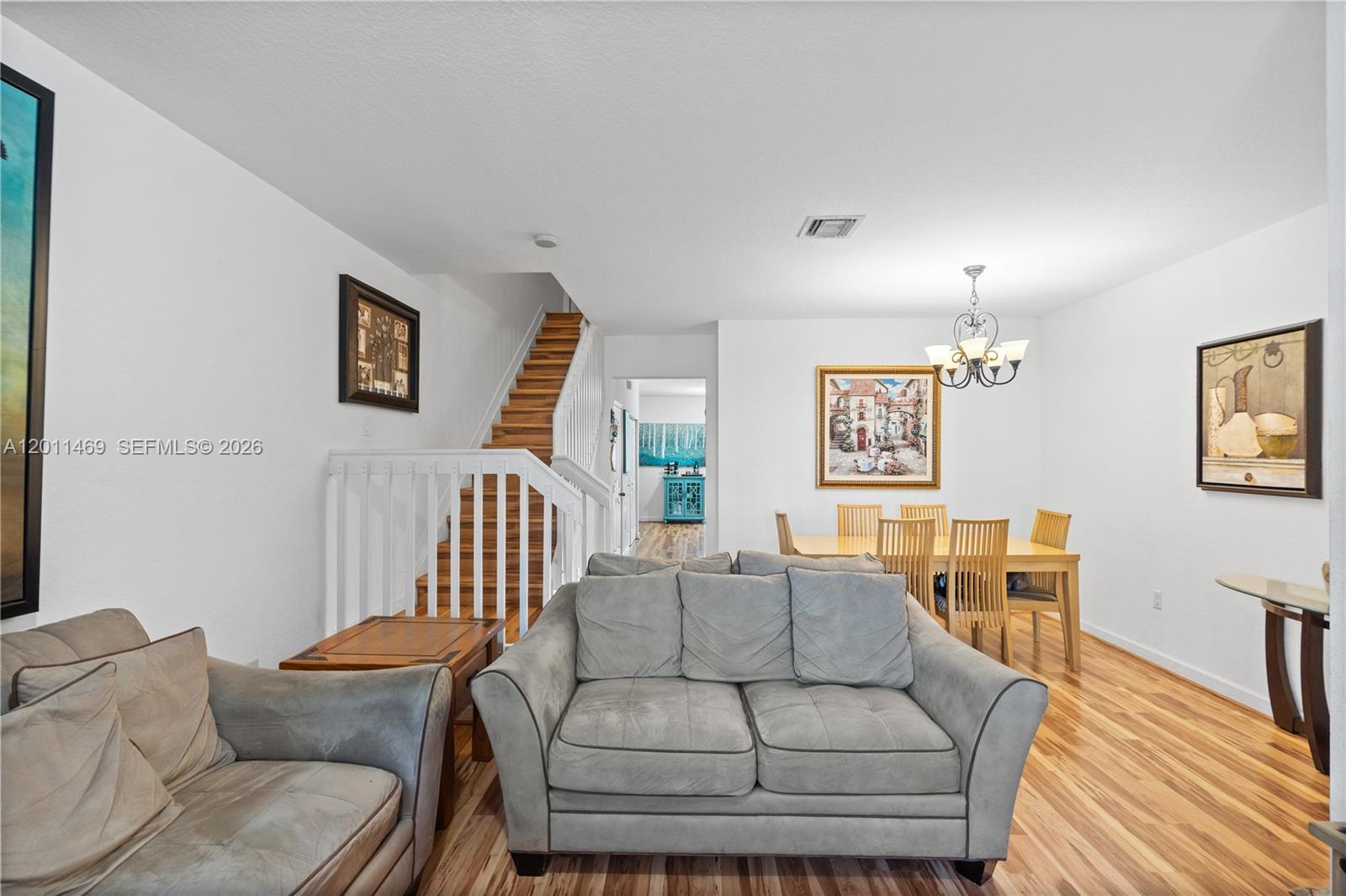 A living room with wood flooring, a staircase, and a dining area in the background — 8430 SW 150th Ave # 2, Miami FL 33193, MIAMI, FL
